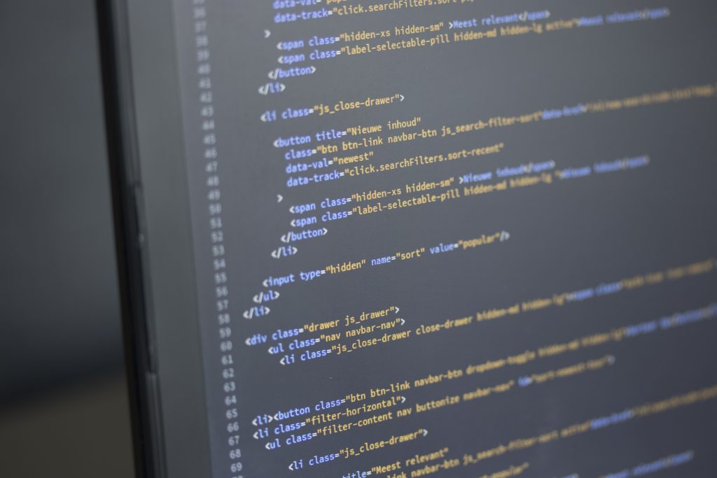Pantalla de monitorización con código y sistemas digitales utilizada para ilustrar servicios de digitalización industrial, trazabilidad y captura de datos en planta